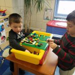 Two boys work at a lego station.